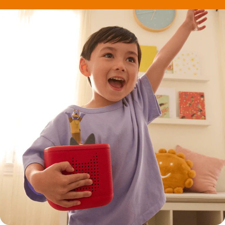 child holding a red Toniebox 2 while listening to the Doggyland Tonie