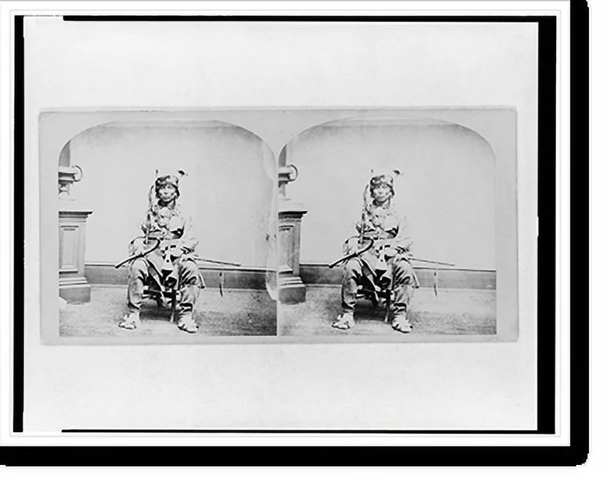 Historic Framed Print, [Winnebago man, full-length portrait, seated, facing front, holding tomahawk and club], 17-7/8